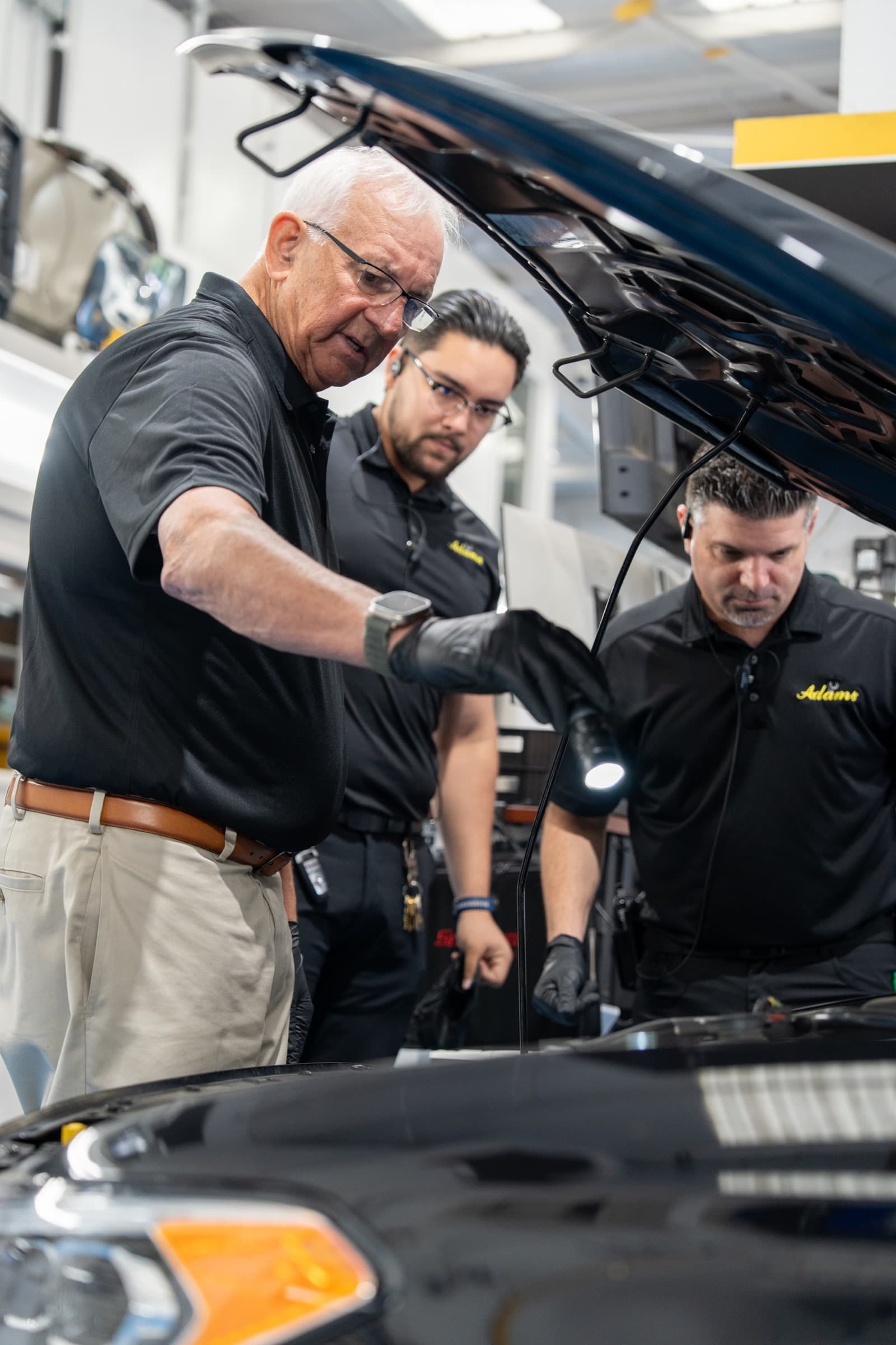 Shop leaders working together around a vehicle in a service bay